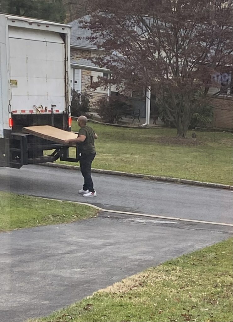 Man unloading Christmas package from delivery truck in driveway