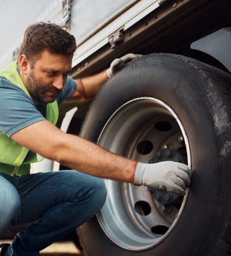 Truck driver inspecting safety of tires before the ride.